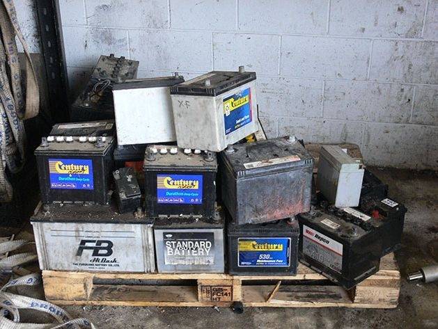 Stacked lead-acid car batteries on a pallet.